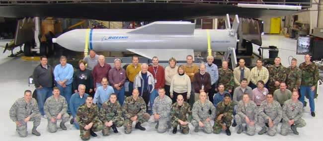 Weapon specialists gather in front of a mock up of the Massive Ordnance Penetrator and the B-2 weapons load trainer Dec. 18 at Whitman Air Force Base, Mo. Photo: USAF