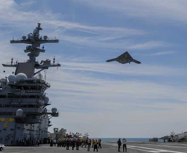 An X-47B Unmanned Combat Air System (UCAS) demonstrator flies over the aircraft carrier USS George H.W. Bush (CVN 77). George H.W. Bush is the first aircraft carrier to successfully catapult launch an unmanned aircraft from its flight deck. (Photo: Northrop Grumman by Alan Radecki)