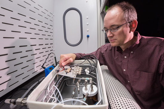 Sandia National Laboratories researcher Chris Brotherton checks tiny sensors in a test fixture, where he exposes them to different environments and measures their response to see how they perform. Brotherton is principal investigator on a project aimed at detecting a common type of homemade explosive made with hydrogen peroxide. (Photo by Randy Montoya)