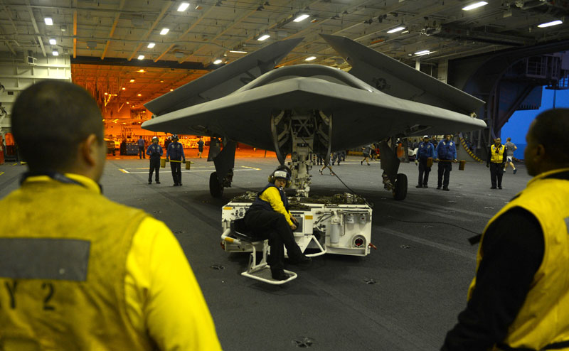 An X-47B Unmanned Combat Air System (UCAS) demonstrator is towed into the hangar bay of the aircraft carrier USS George H.W. Bush (CVN 77). (U.S. Navy photo by Timothy Walter)